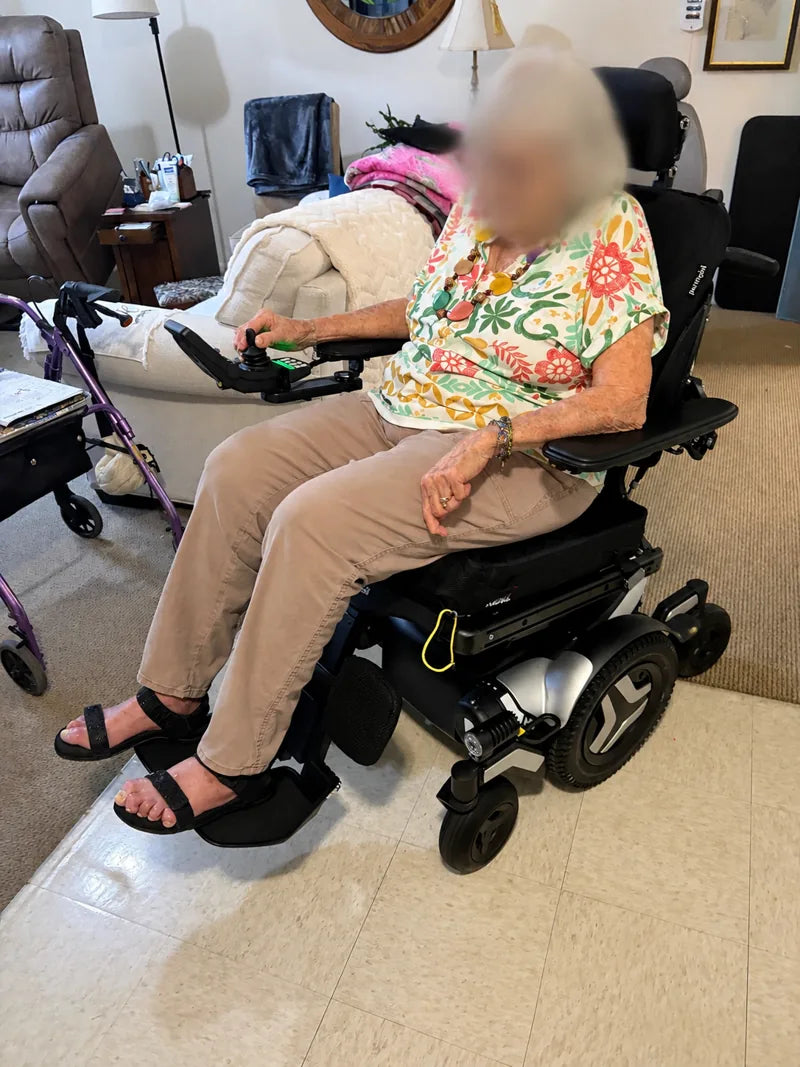 Medical Equipment Specialists client seated in a power wheelchair at home, face blurred for privacy